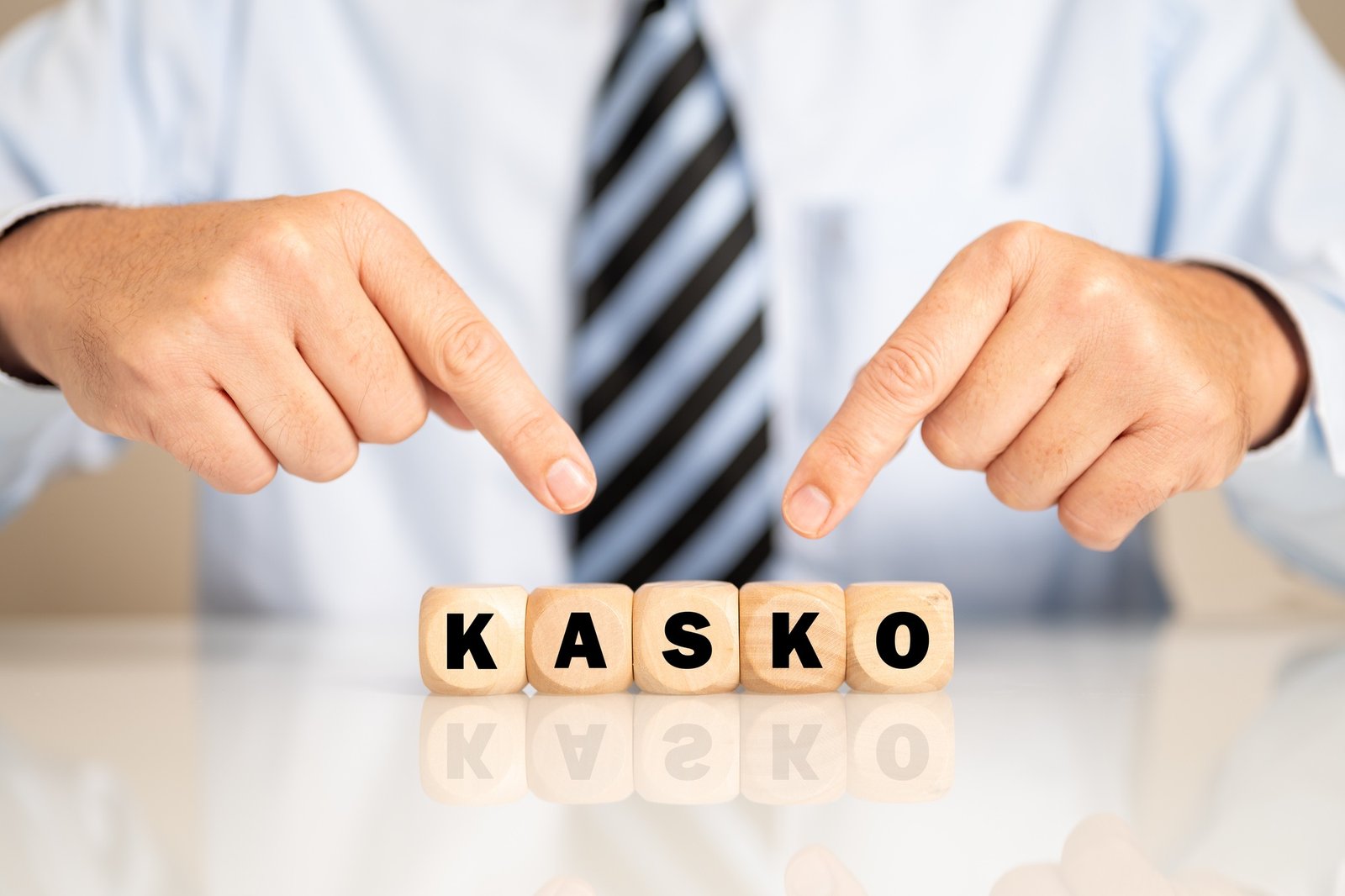 Businessman pointing to the wooden blocks with the word 'kasko' written on it