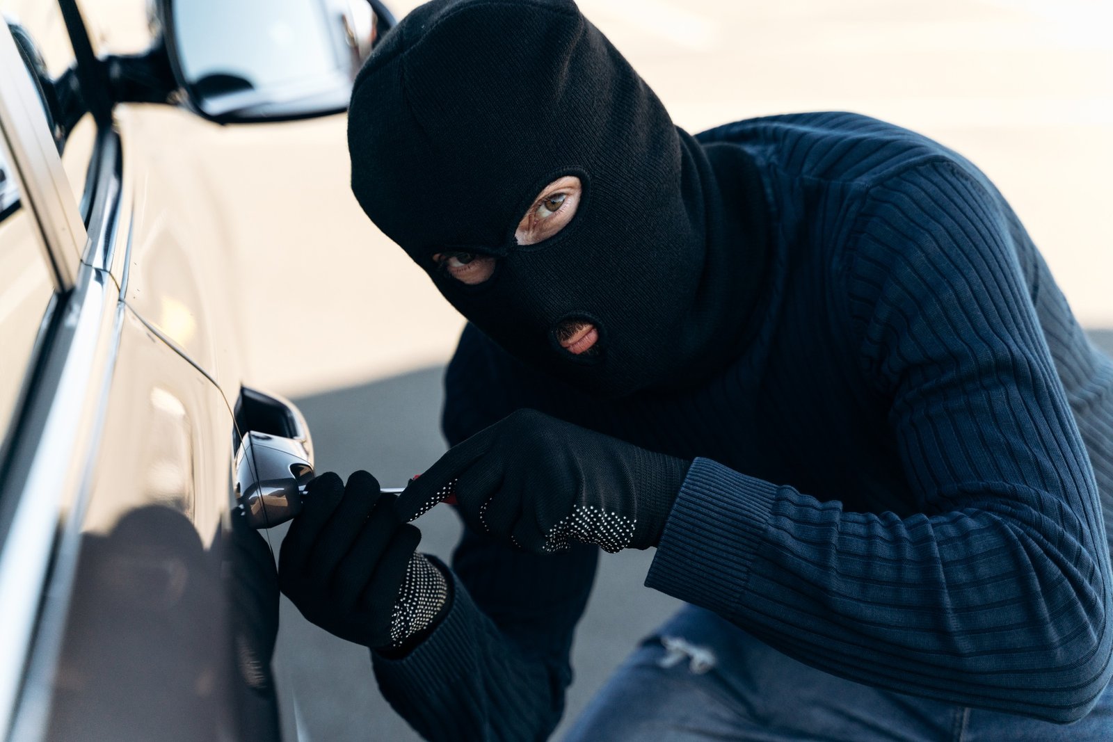 Thief trying to break into the vehicle, car thief trying to break into a car with a screwdriver